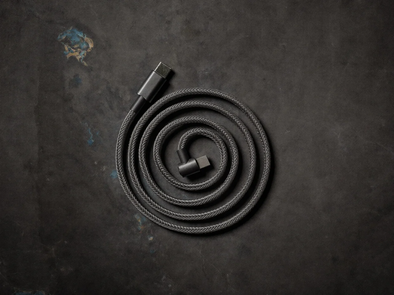 Geflochtenes USB-C-Ladekabel als präzise Spirale auf grauem Stein
